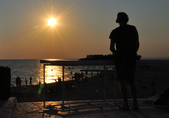 DJ plays music on the beach at sunset