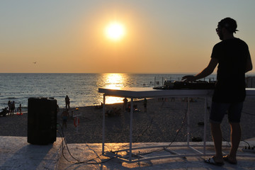 DJ plays music on the beach at sunset