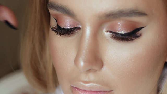 Make-up artist makes make-up eyelashes in a young woman