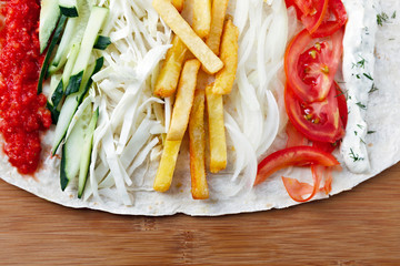 Ingredients for cooking shawarma lie on a pita bread. Middle Eastern dish to grill.