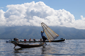 Travel Asia, Myanmar (Burma). Tourists photographing traditional Burmese fisherman posing for them at Inle lake.