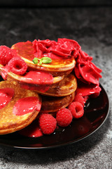 Pancakes with berries and maple syrup on rustic table