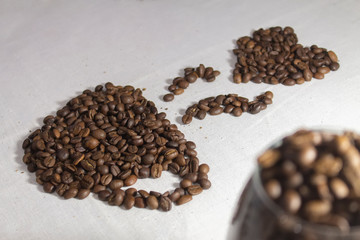 cup of coffee laid out of roasted coffee beans on tablecloth