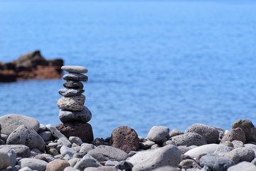 Stacked stones against on the coastline against blue water