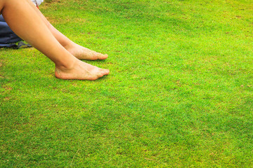 Woman with bare legs relaxing in grass of a park background during summer sunny day. Holidays...