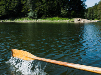 Fototapeta premium Oar of boat touching water and causing splash and ripples in the water A wooden paddle on a boat Blade of wooden kayak or canoe paddle Water splash 