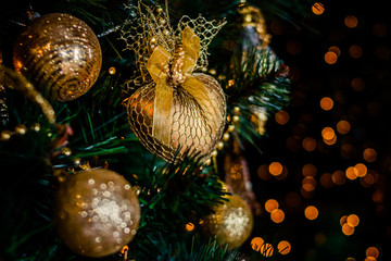 Obraz na płótnie Canvas Fir branch with balls and festive lights on the Christmas background with sparkles.Golden Ball with Glitter as Decorative Christmas Ornament on a Artificial Tree.New year decoration.Selective focus