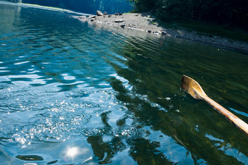 Oar of boat touching water and causing splash and ripples in the water A wooden paddle on a boat Blade of wooden kayak or canoe paddle Water splash  
