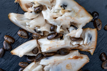Close-up of ripe custard apple. Open fruit, with nuggets and spoon on dark background.