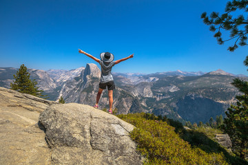 Travelling enthusiast woman happy for the Glacier Point aerial view in Yosemite National Park, California, US. Glacier Point panorama: Half Dome, Liberty Cap, Yosemite Valley, Vernal Fall, Nevada Fall