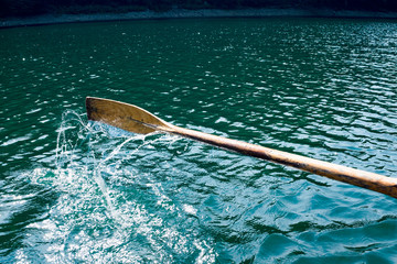 Oar of boat touching water and causing splash and ripples in the water A wooden paddle on a boat Blade of wooden kayak or canoe paddle Water splash  