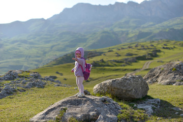 Naklejka na ściany i meble A little funny girl travels in the mountains.