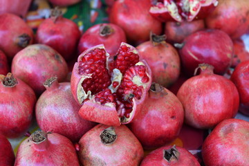 A heap of pomegranates with an opened one in the middle on a market in Mexico.