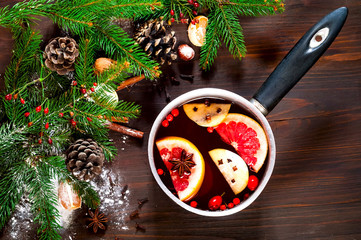 Fototapeta na wymiar Christmas background. Hot mulled wine with ingredients in authentic ladle on wooden background. The concept of celebration and cooking warming drinks.Top view, close up, copy space