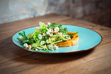 Salad with gorgonzola, pumpkin and greens on the plate