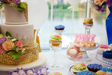 Obraz na płótnie Canvas Candy bar on golden wedding party with a lot of different candies, cupcakes, souffle and cakes. Decorated in brown and purple colors, nature and eco theme, indoor