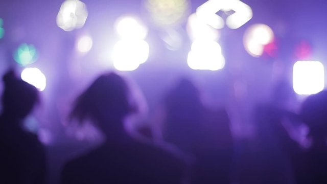 People dance in a club in blur . Back view