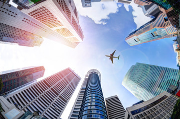 Obraz premium Koncepcja biznesowa z samolotem lecącym nad nowoczesnymi drapaczami chmur w Singapurze