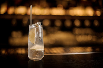 Delicious Tom Collins cocktail in the glass with tubule and lemon