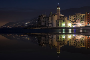 Fototapeta na wymiar Nightly reflections of the town of Camogli. Image made with two overlaid photographs.
