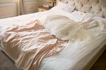 Fototapeta na wymiar Bride's beige dress lies on the bed in a hotel room