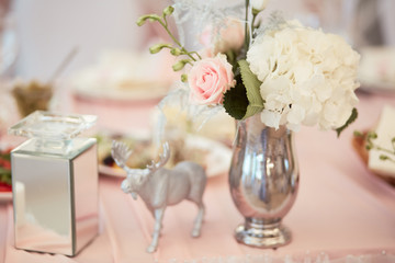 Wedding table festive service. Dinner table decorated with silver statues and vases with white flowers and feathers