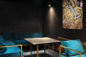 Modern lounge bar interior.Dark tone.Dark cyan sofa and chairs.Golden laterns in form of tubes.