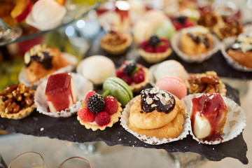 Wedding candy bar. Dishes with delicious sweets, cookies and chocolate cakes stand on the dinner table