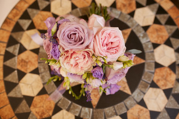 Look from above at violet wedding bouquet standing on the wooden table
