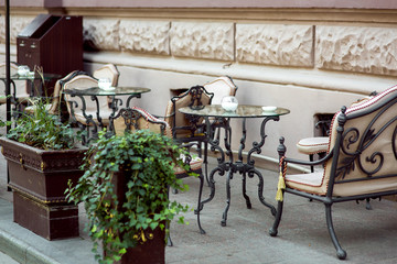 A table with iron forged legs and a glass table top with forged chairs and soft seats on the...
