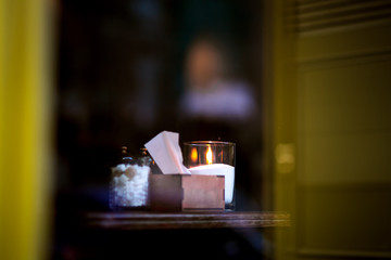 Restaurant table through the glass from the street, a romantic evening with candles in a glass on the table..