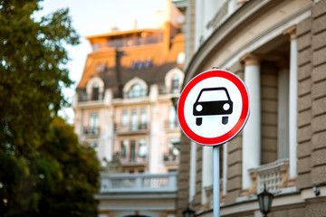A car sign prohibiting the passage of passenger cars, a round sign with a red border on a white background is installed near an architectural building in a European city.