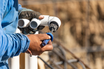 Plumber Applying Pipe Cleaner, Primer and Glue to PVC Pipe At Construction Site