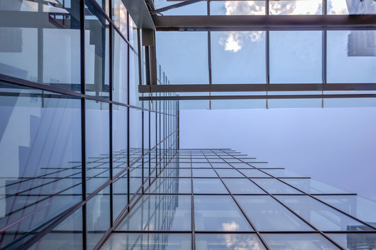 Angled view of a glass wall of an office building. Infinity effect in the blue sky.