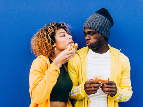 African man and latin woman eating hamburger together.