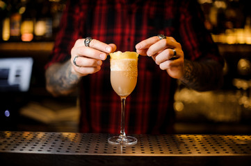 Bartender decorate a white achoholic drink in cocktail glass with zest