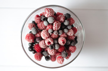 the frozen berries raspberry and currant in a glass plate on a white background