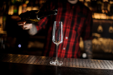Bartender pourring a champagne from a bottle to a glass