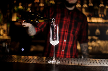 Professional bartender pourring a champagne from a bottle to a glass
