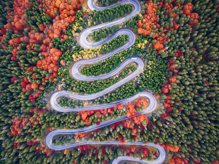 Beautiful aerial view of mountain landscape in autumn time with curvy road cutting through forest....