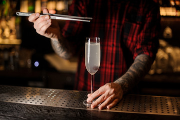 Bartender adding berry to a delicious cocktail French 75