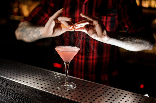 Professional bartender adding an orange zest juice to a Cosmopolitan cocktail
