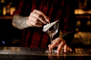 Barman decorating cocktail glass with a paper plane