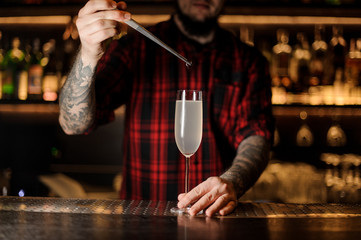 Barman putting a cherry into a French 75 cocktail