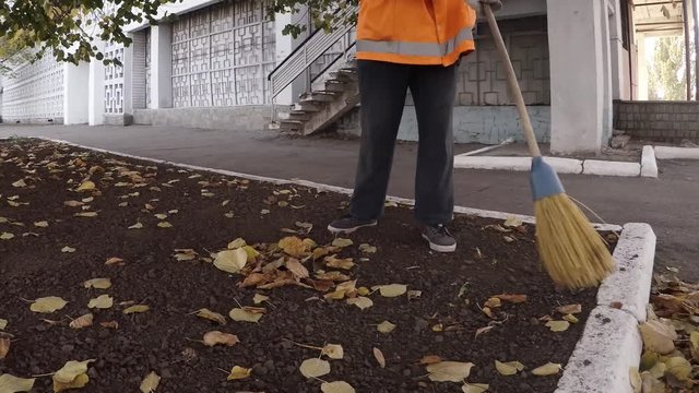 Woman janitor cleaning park from leaves in autumn, most hard and low-paid job