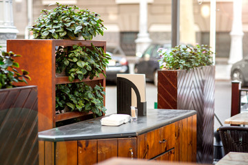 countertop bedside tables with shelves and pots with plants in the street restaurant, an empty cafe nobody.