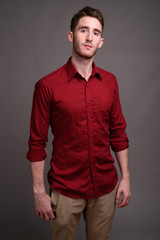 Fototapeta premium Young handsome businessman wearing red shirt against gray backgr
