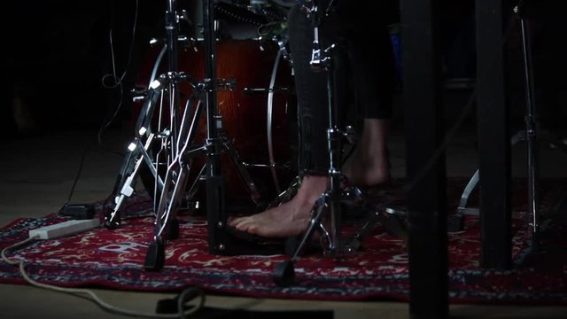 Wide shot of female drummer playing foot pedals on drum kit
