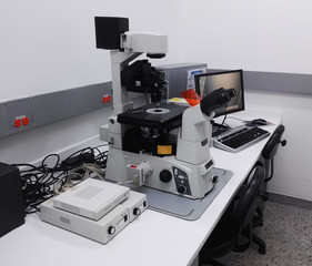 Desk with a high-tech microscopy station in a scientific laboratory. High magnification inverted...