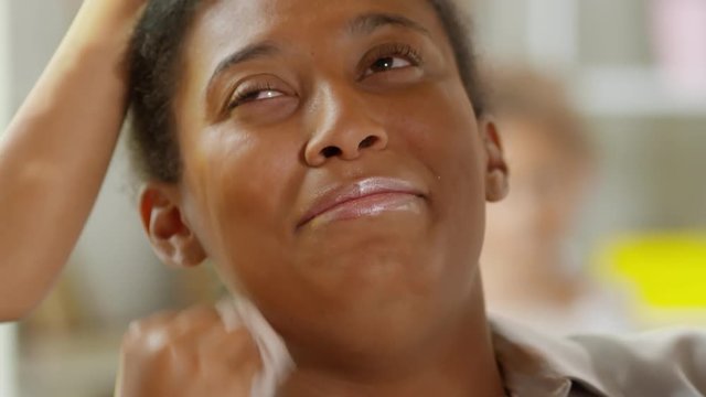 Close up face of black woman talking and laughing while unrecognizable daughters applying and removing makeup from her face